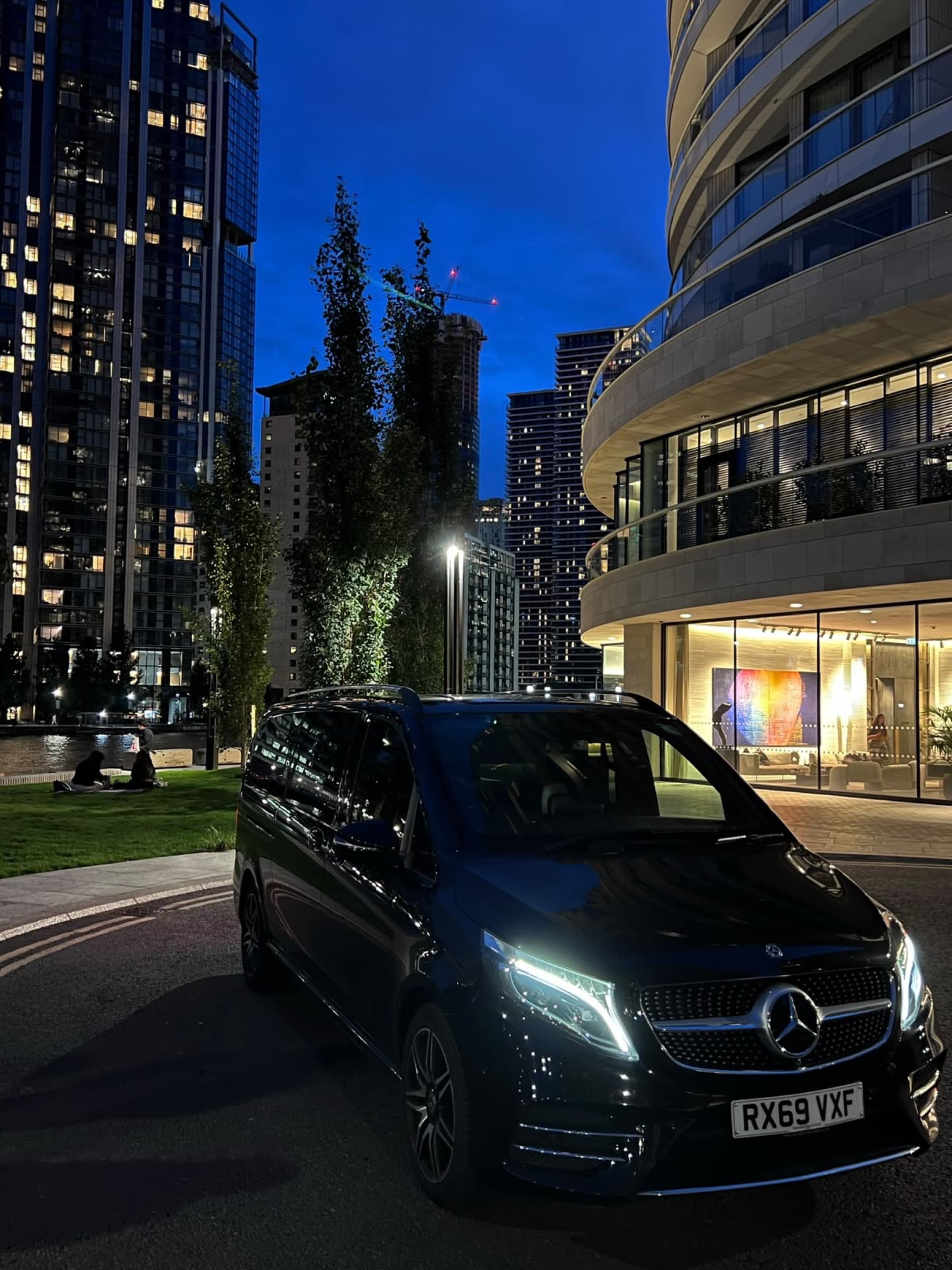 A chauffeur from AC Chauffeurs beside a Mercedes S-Class outside a client's office